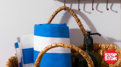 Blue and white striped beach towels in woven baskets with a bottle of sunscreen.