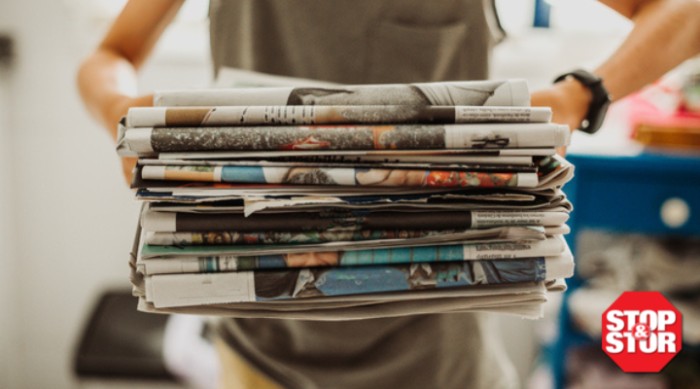 woman holding a stack of newspapers