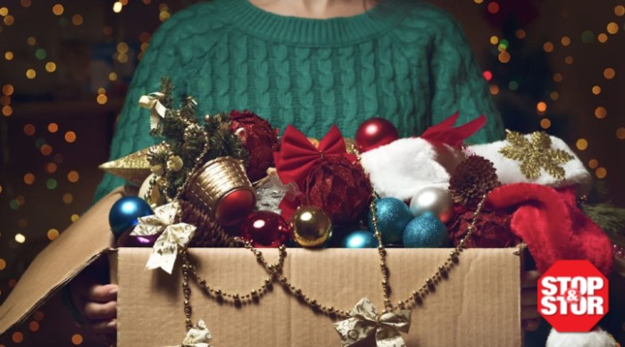 woman wearing sweater holding christmas storage box full of ornaments