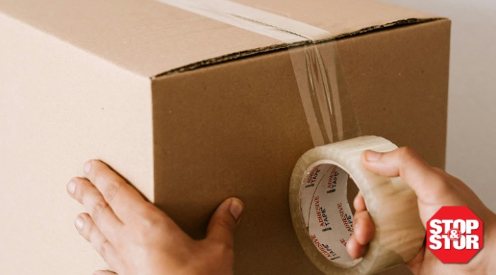 person taping a cardboard box for storage