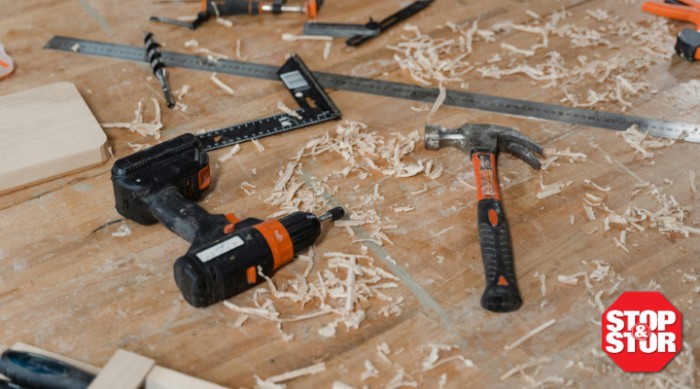 a drill and hammer laying on a dirty shop bench