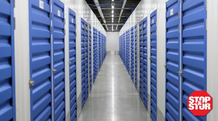 Long hallway lined with blue self-storage unit doors inside a clean, climate-controlled Stop & Stor facility, illustrating secure storage with transparent, guaranteed self-storage rates in NYC.