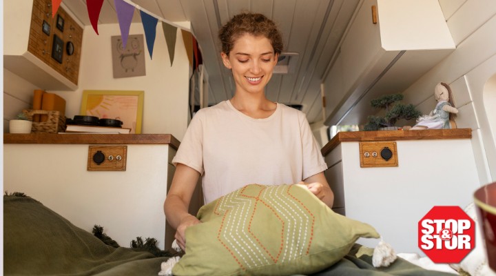 Woman arranging a decorative pillow inside a tiny home.